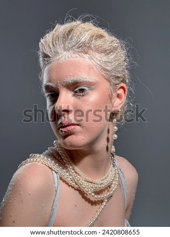 Portrait of a blonde girl in snowflakes. Photo in the studio