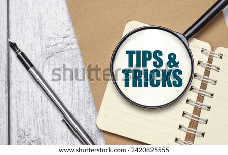 TIPS AND TRICKS words on magnifying glass with pen and papers