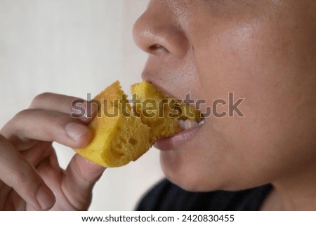 A PICTURE OF A PERSON EATING A SERABE CAKE MADE FROM RICE FLOUR
