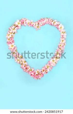 Heart shaped wreath with apple blossom flowers for Spring Beltane and Easter. Abstract floral design for birthday Mothers Day card, logo, gift tag or invitation on blue.  Royalty-Free Stock Photo #2420851917
