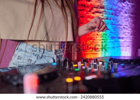 control DJ for mixing music with blurred people dancing at party in nightclub.