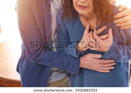 First aid in heart attack. Senior male helps female with heart disease and chest pain Royalty-Free Stock Photo #2420885503