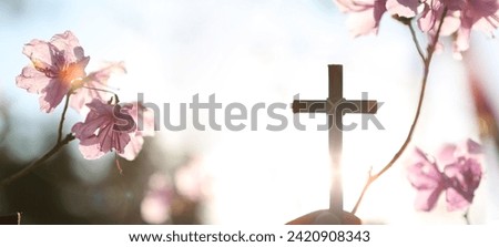 Background with strong sunlight shining through azalea flowers on a spring day and a Christian holding the holy cross of Jesus Christ in his hands
