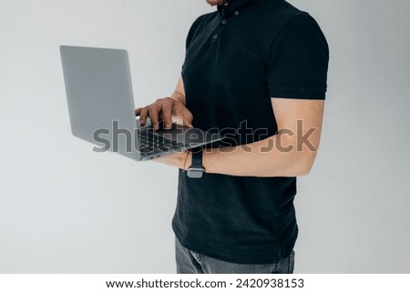 A freelancer in a black polo shirt works at a computer. Stylish business portrait of a man and laptop, close-up photo. 