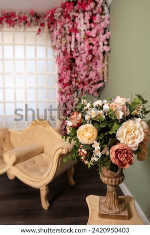 beige sofa on the background of a wooden frame with sakura flowers. wedding photo zone in the photo studio with pink flowers. a photo zone with furniture and artificial flowers and a wooden lattice