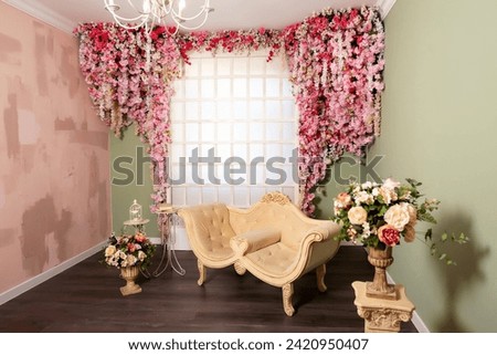 beige sofa on the background of a wooden frame with sakura flowers. wedding photo zone in the photo studio with pink flowers. a photo zone with furniture and artificial flowers and a wooden lattice