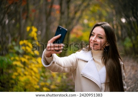 Young beautiful woman takes selfie in the autumn park