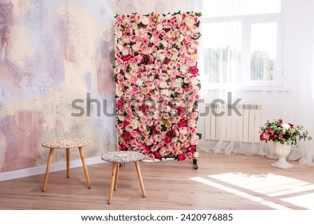 metal frame decorated with artificial flowers with wooden tables. spring photo zone in the photo studio. ready-made light photo zone with artificial flowers