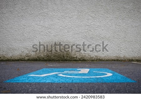 Disabled parking sign painted on the ground of a car park. Parking lot space for persons with disability.