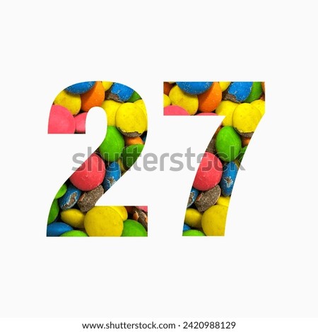 Number twenty seven of colourful candies and paper cut in shape of twenty seventh digit isolated on white. Rainbow typeface
