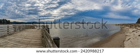 Old wooden pier over bay ocean waters with beautiful sunny sky and sandy beach in panoramic format. No data licensing. Royalty-Free Stock Photo #2420988217