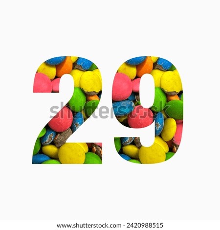 Number twenty nine of colourful candies and paper cut in shape of twenty ninth digit isolated on white. Rainbow typeface