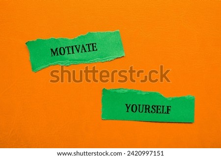 Motivate yourself lettering on ripped green paper pieces with orange background. Conceptual photo. Top view, copy space.