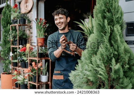 Young man smiles in plant store.
concept: small plant and nursery business. Royalty-Free Stock Photo #2421008363