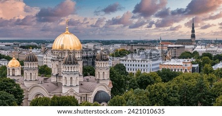 The Nativity of Christ Cathedral in Riga, Latvia. Byzantine-styled Orthodox cathedral, the largest in the Baltic region, with golden colored dome, polished gilded cupolas gleaming through the trees Royalty-Free Stock Photo #2421010635