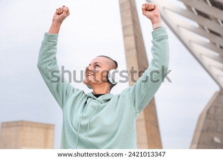  portrait sporty woman smiling with arms up outdoors.