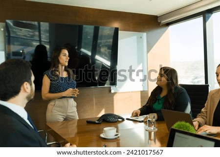 Female boss doing a performance review with memebers of her team and talking in a meeting room