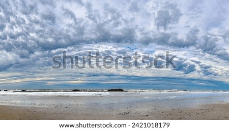 Beautiful blue sky and dramatic clouds over the ocean shoreline in panoramic format. No data licensing. Royalty-Free Stock Photo #2421018179