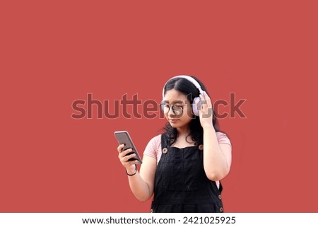 Female Latina teenager of 17 years old uses her cell phone and audio to connect to music, podcast audiobooks and songs with her friends