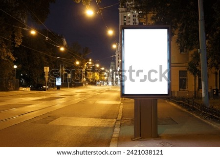 Vertical billboard advertising in the night city. Yellow street lighting with tram rails. Mock-up.