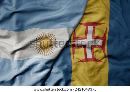 big waving national colorful flag of madeira and national flag of argentina . macro
