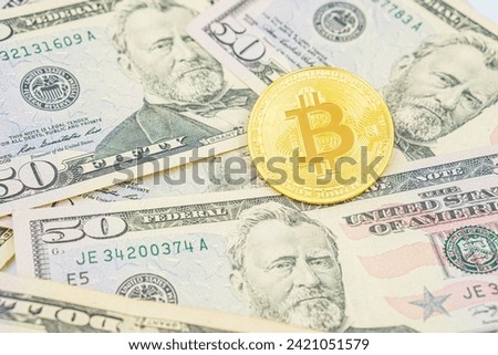 Bitcoin cash BTC, cryptocurrency pictured as a gold, gold coin lying over dollars, real US money, 50 dollars, United States fifty-dollar bill. Bitcoin on top of United States Dollar Banknotes.