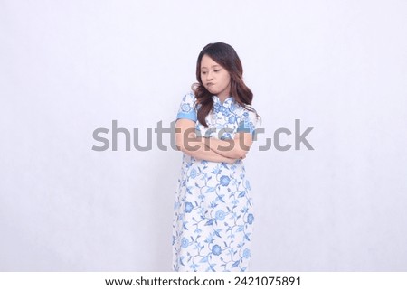 beautiful pouting Javanese Chinese woman wearing a modern Chinese dress with arms crossed on a white background. happy Chinese New Year