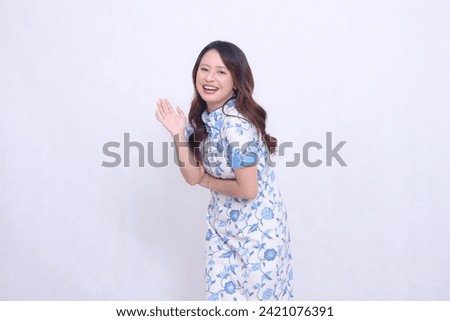 Beautiful indonesian woman wearing modern chinese dress hand sign hello isolated on white background. happy Chinese New Year