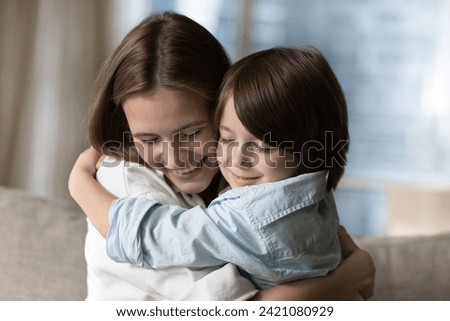 Close up shot young mommy tightly cuddling her cute little 5s son, loving family enjoy hugs with eyes closed, spend time together at home. Happy Mother Day, motherhood, upbringing, unconditional love Royalty-Free Stock Photo #2421080929