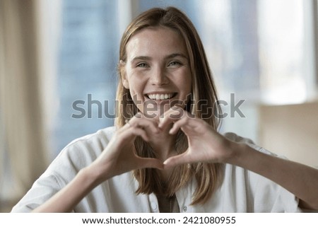 Head shot close up portrait happy woman showing heart symbol gesture with fingers, make love sign, express sincere feelings, looks at camera. E-dating services, donation campaign, loyalty, I Love You
