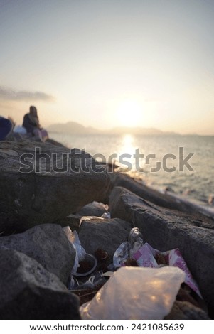 sunset View. rubbish on rocks. watching the sunrise from the top of the breakwater embankment