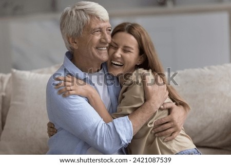 Happy loving senior father embracing joyful adult daughter woman with affection, smiling, laughing, telling funny story, giving comfort, support, care, enjoying being parent, fatherhood Royalty-Free Stock Photo #2421087539