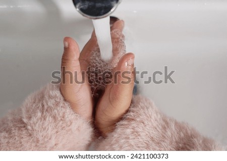 child washing hands with warm water 