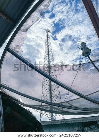 Communication tower amid tv satellite dishes against a blue sky