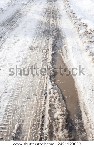 winter snowy road with puddles