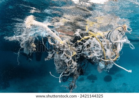 Abandoned debris fishing net or ghost net and plastic garbages in the sea. Clean up the ocean by collecting waste. Save the ocean and underwater world from trash pollution. Environmental conservation Royalty-Free Stock Photo #2421144325