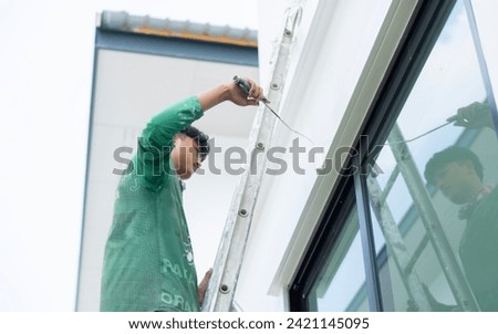 House painting and renovation business concept. 

Asian male painting wall outstide house from the ladder. Construction concept. Royalty-Free Stock Photo #2421145095