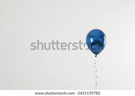 Blue balloon with sad face on light grey background. Space for text