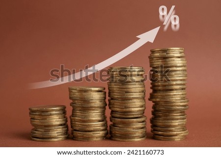 Mortgage rate. Stacked coins, arrow and percent sign on brown background