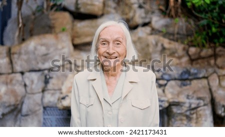 Great grandmother smiling at camera in a nursing home Royalty-Free Stock Photo #2421173431