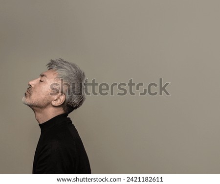 Portrait of a handsome middle-aged man with gray hair and a beard.He has his chin up and his eyes closed. Royalty-Free Stock Photo #2421182611