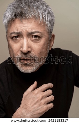 A middle-aged Japanese man with a beard and gray hair with serious expression. Royalty-Free Stock Photo #2421183317