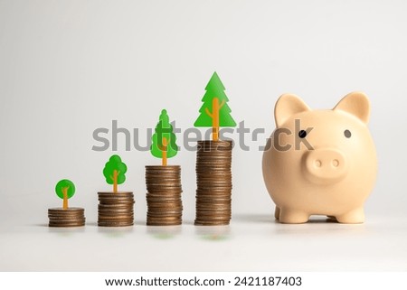 A visual metaphor for financial growth featuring coin stacks and a piggy bank with tree symbolizing increasing investments. Royalty-Free Stock Photo #2421187403