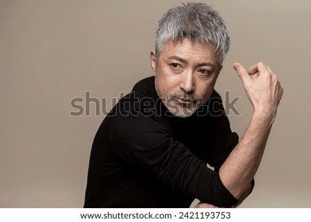 A middle-aged Japanese man with a beard and gray hair with serious expression. Royalty-Free Stock Photo #2421193753