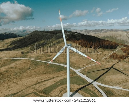 Giant Among Giants: Wind Turbine Overlooking Autumn Valleys Royalty-Free Stock Photo #2421212861