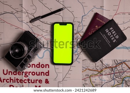 Travel planning London with notes, camera, passport and green screen smartphone