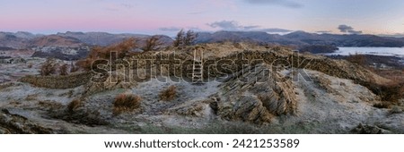 Lake District sunrise panorama seen from Black Crag with wooden stile over stone wall. Aerial views towards Windermere and Langdale. Royalty-Free Stock Photo #2421253589