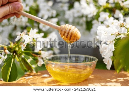 Natural Honey Dripping from Dipper into Bowl Outdoors