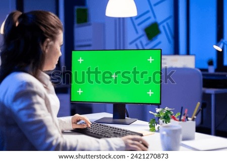 Entrepreneur working in front of green screen display sitting at desk during videocall meeting in business office. Businesswoman watching desktop monitor with green mockup, chroma key, working