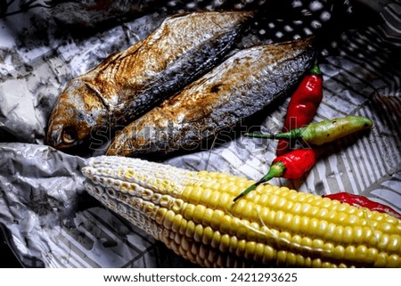 corn and two salted fish on a paper package, dried and salted sea fish.